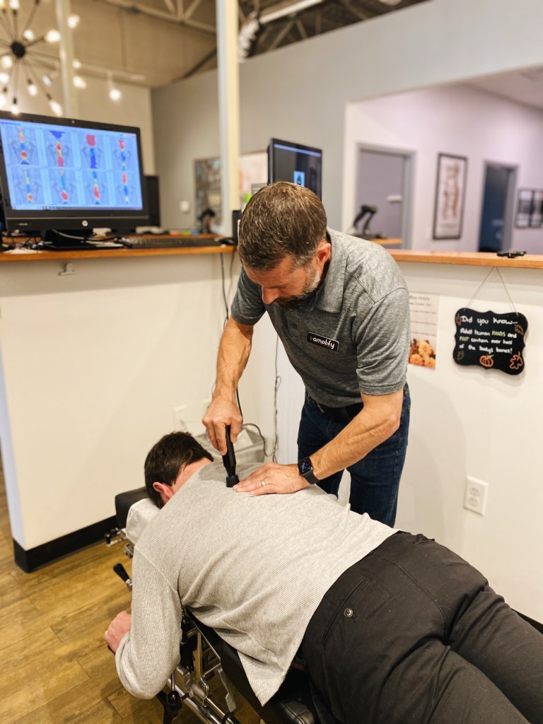 Dr. Schulz using a handheld adjusting instrument on a patient's upper back