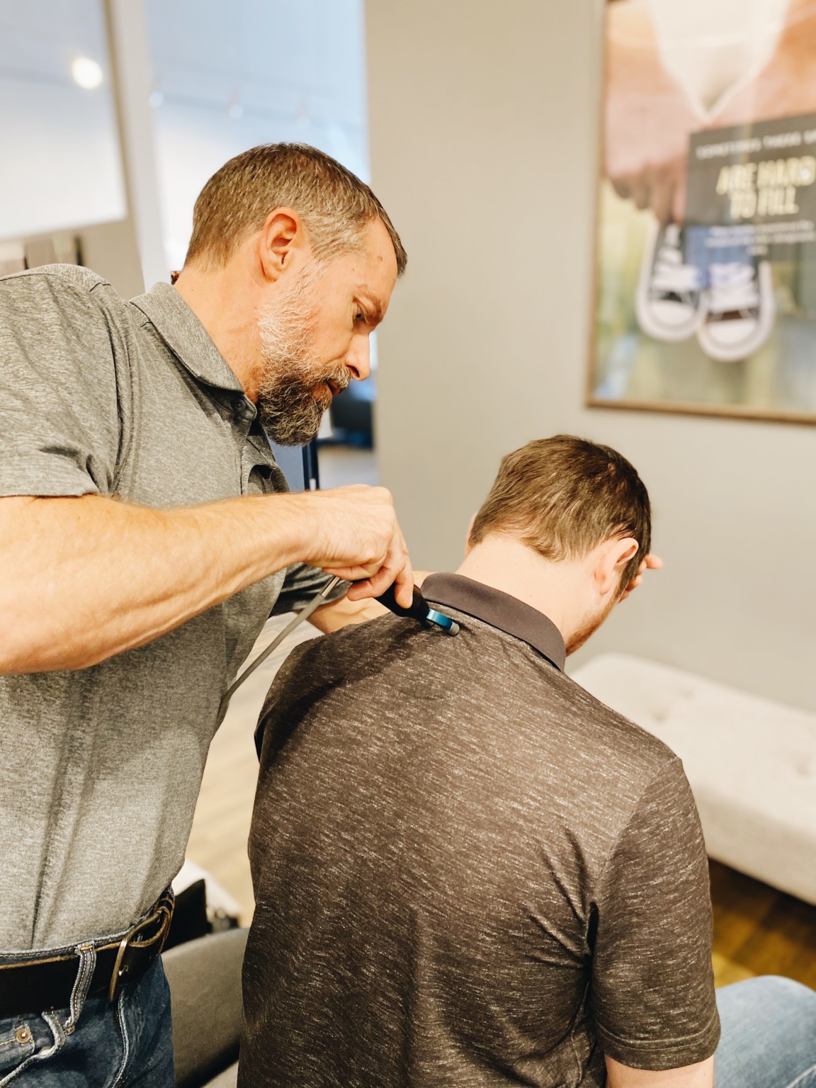 Dr. Schulz using a handheld adjusting instrument at the base of a patient's neck